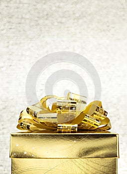 Close up Golden present box with big bow at bokeh white blur background, Leave space on top to adding your content photo